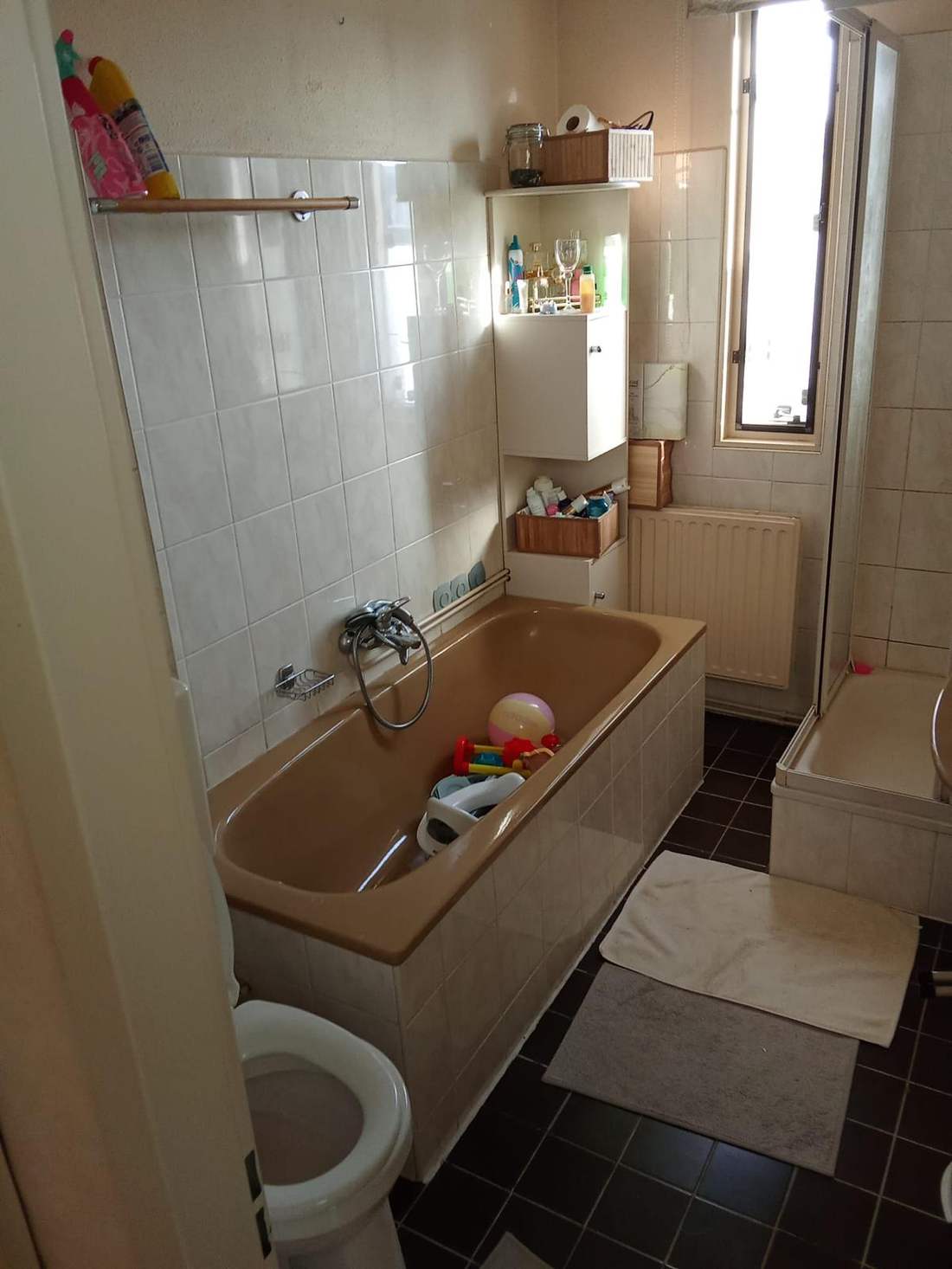 Gedateerde badkamer met roze bad voor de renovatie