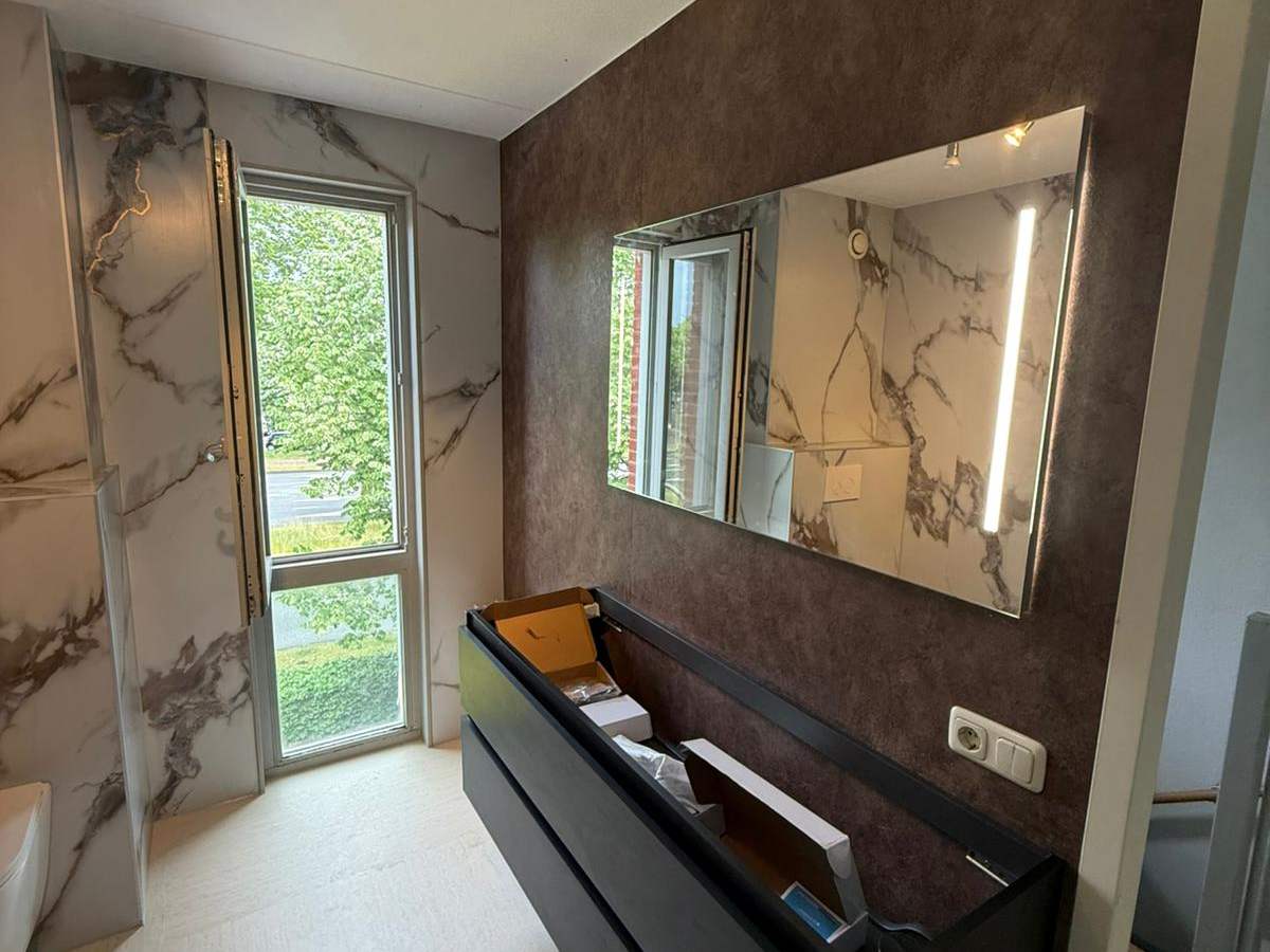 Lichte badkamer met marmerlook wanden en ligbad
