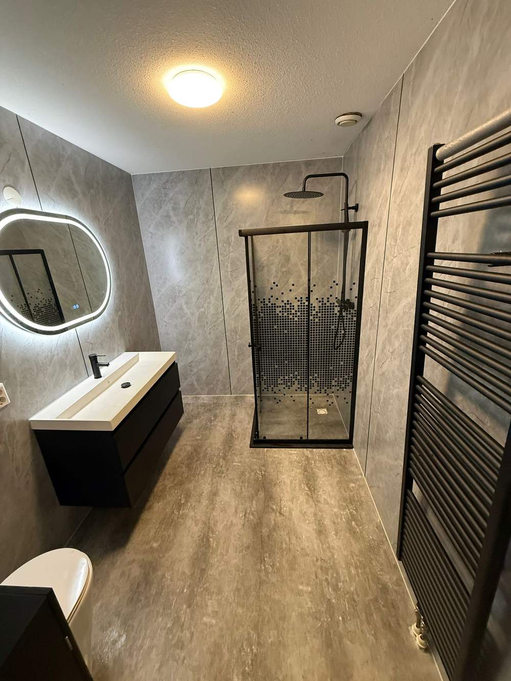 Badkamer met zwart douchescherm en zwarte handdoekradiator