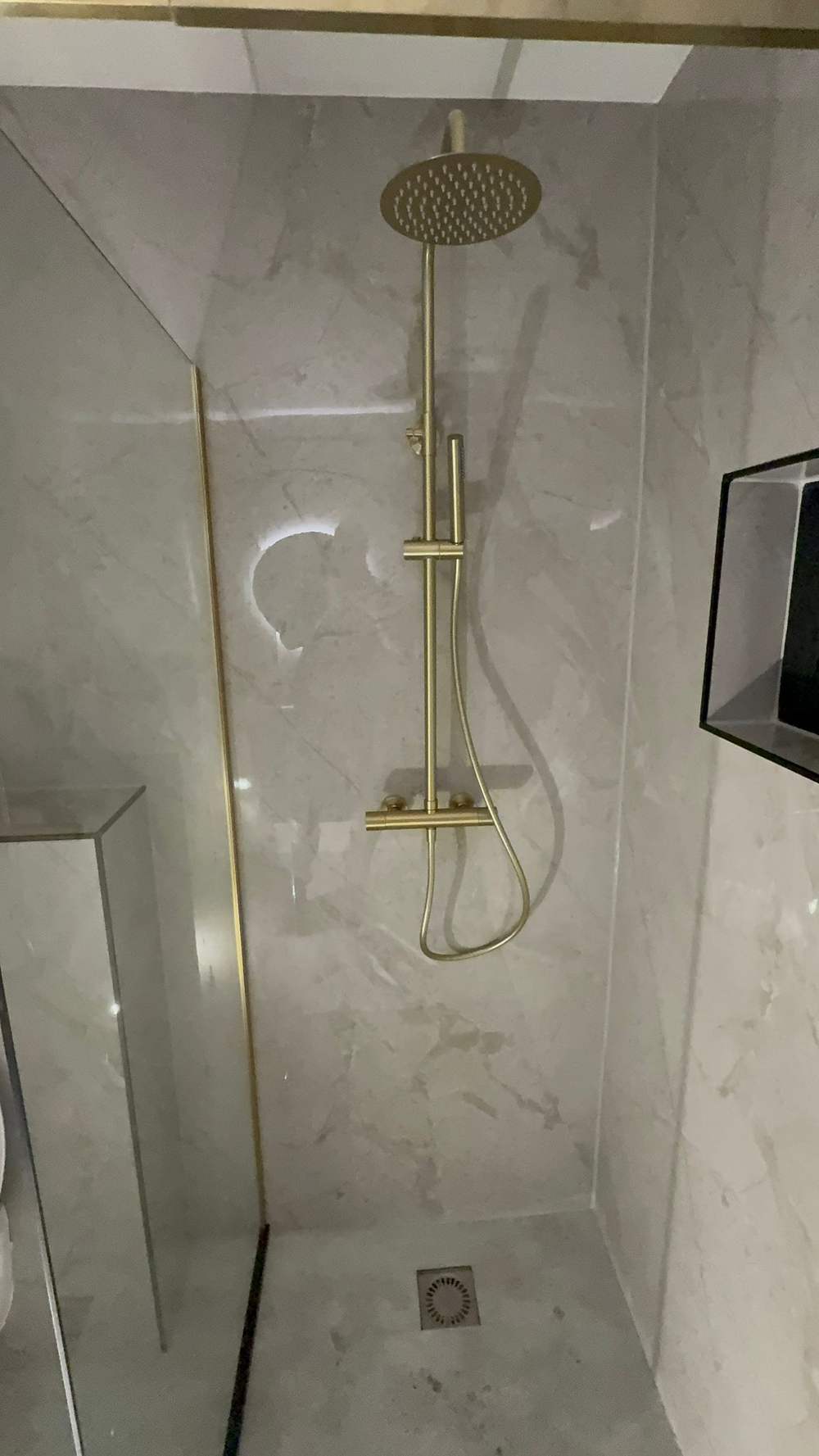 Gouden douchekolom op marmerlook wandpanelen