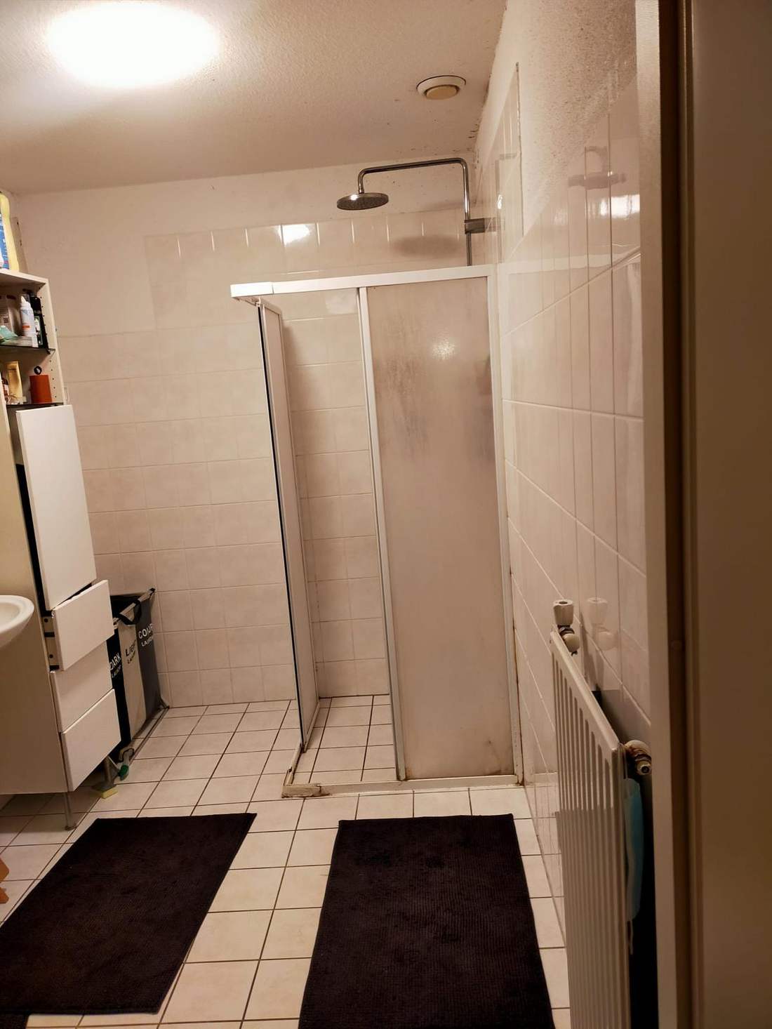 Oude badkamer met witte douchecabine voor de renovatie